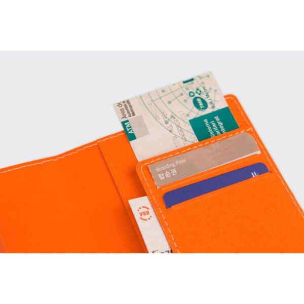 Reisepasshuelle Passport Case Tangerine aus Cellulosepapier befuellt mit Tickets und zwei Karten.